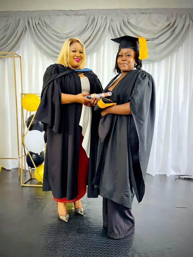 A graduate holding her certificate with a facilitator